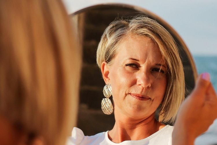 A midlife woman looks in the mirror.
