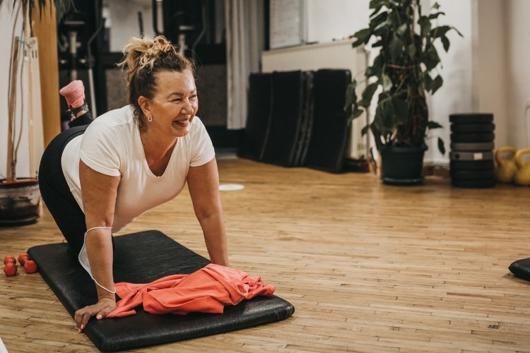 A woman cultivates inner peace while working out on a yoga mat on the floor.