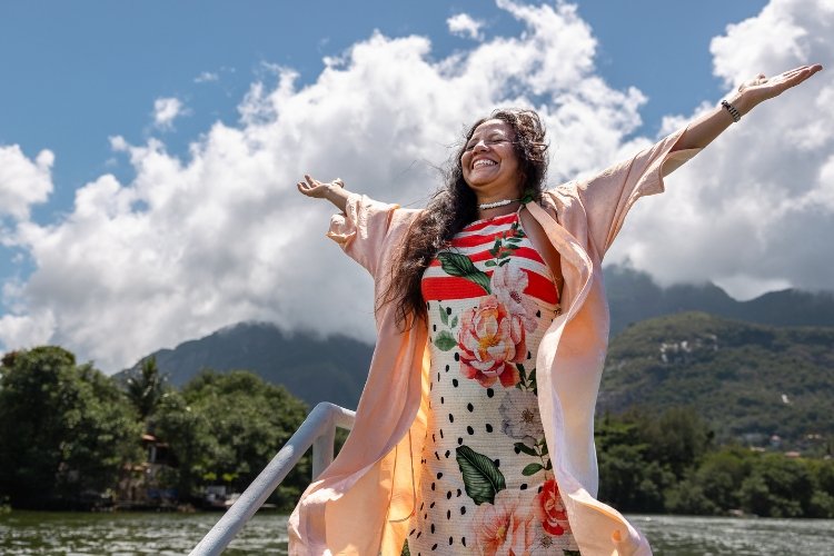 A woman stands arms spread with gratitude against a stunning mountain scene.