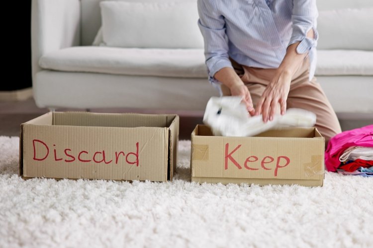 While spring cleaning, a woman declutters by sorting items into boxes marked “keep” and “discard.”