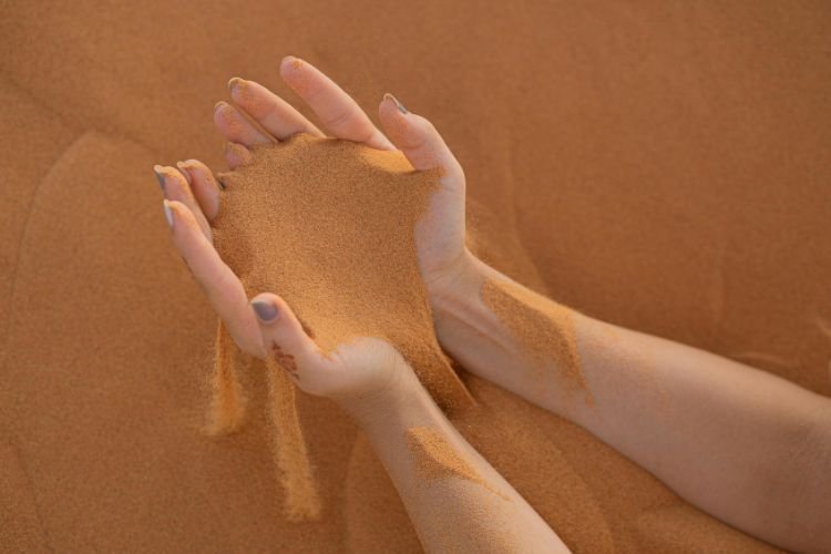 Sand falls through a woman's hands as she masters the art of letting go.