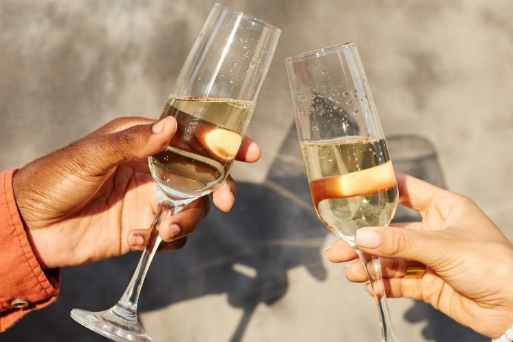Two women raise glasses of sparkling wine as a celebration of self-worth in midlife.